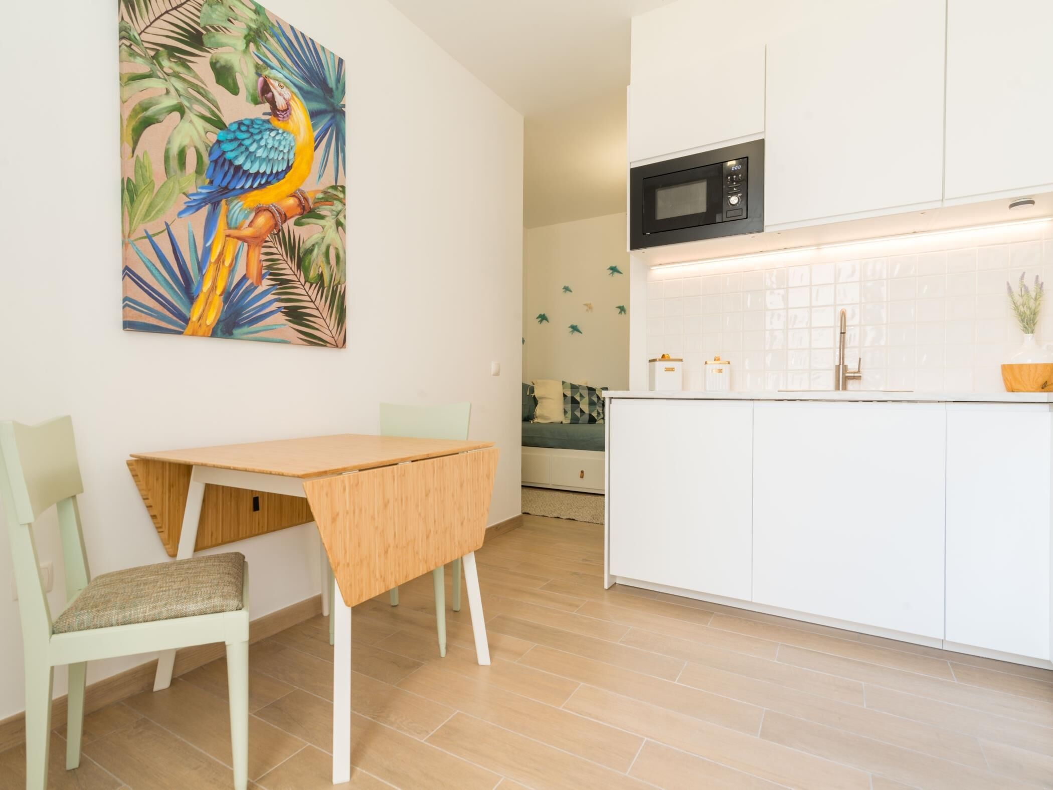 A modern kitchen with white cabinets, a microwave, and a tiled backsplash.