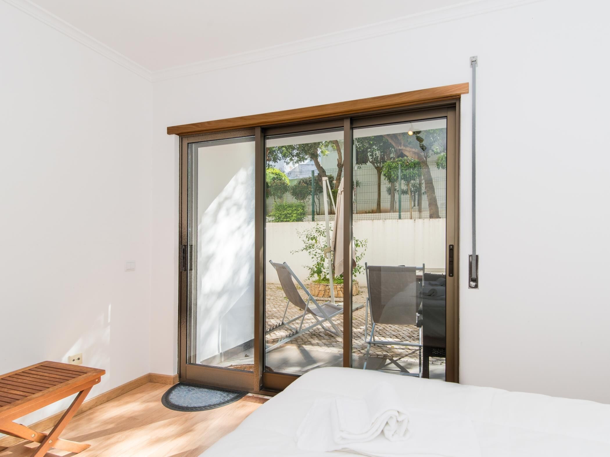 A bedroom with a sliding glass door leading to an outdoor seating area with a table and chairs.