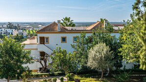 Un bâtiment blanc, doté d’un toit en tuiles, entouré de verdure et offrant une vue sur la côte.
