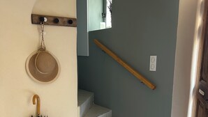 A staircase with a wooden handrail, a hat hanging on the wall, and a decorative umbrella on the floor.