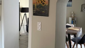 A dining area with a table set for two, a lamp, and a painting of sunflowers on the wall.