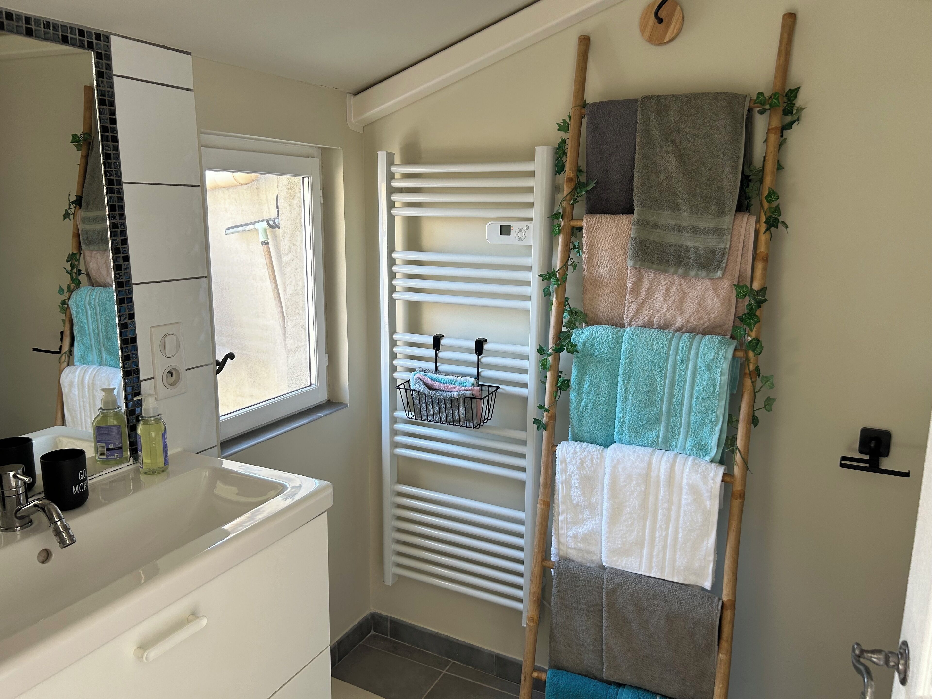 A bathroom with a white sink, mirror, and towel rack.