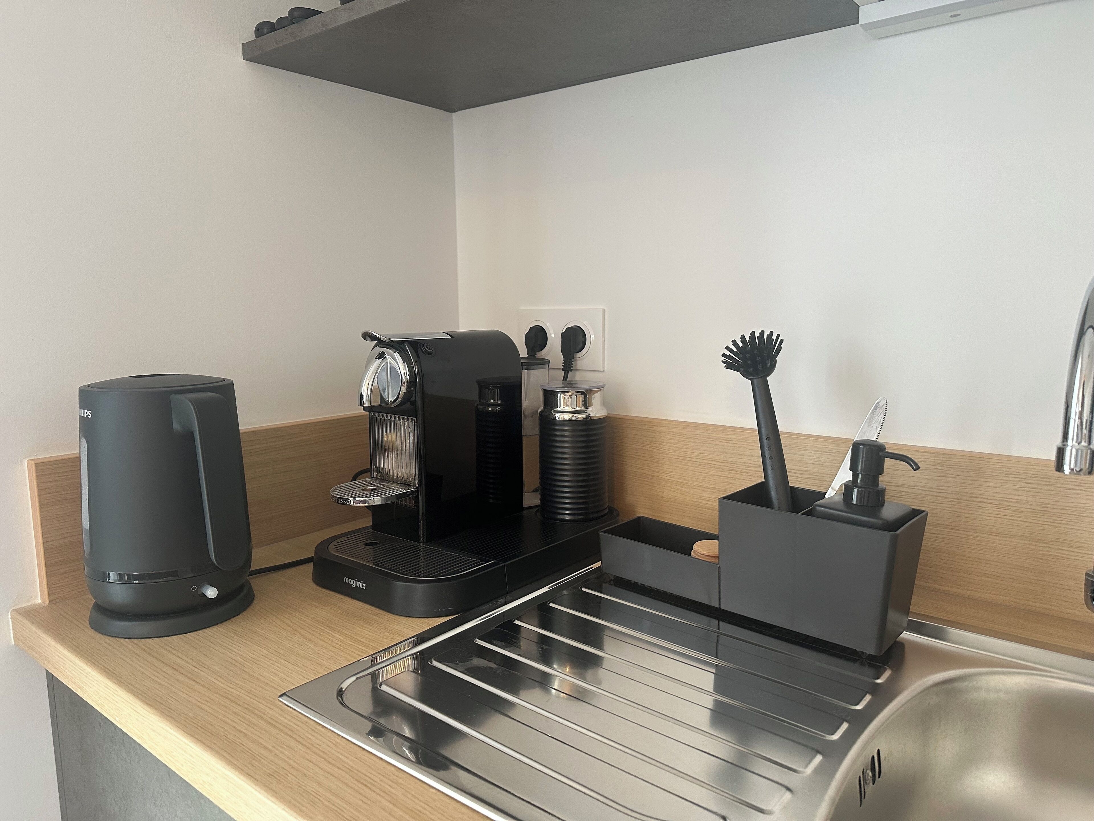 Una cocina moderna con cafetera, hervidor y pileta.