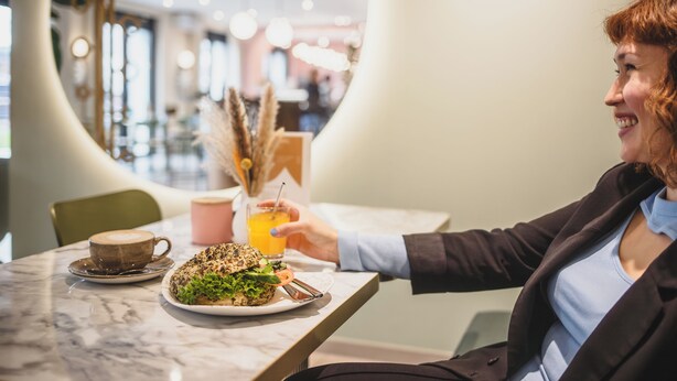 A person sitting at a table with a plate of food, a drink, and a cup. - The Circus Living (Berlin)