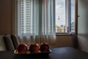 Ein Zimmer mit Blick auf einen Turm und Gebäude durch ein Fenster mit Jalousien.