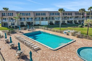 A hotel with a pool area, including lounge chairs and umbrellas, and a building with multiple balconies. - Direct Ocean View, Private Washer & Dryer (Saint Augustine Beach Florida)