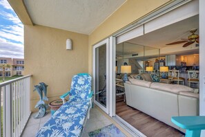 Un balcón con un sofá, una silla y elementos decorativos.
