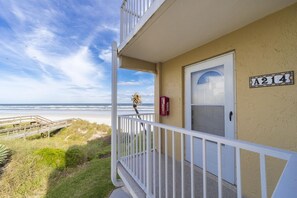 Une propriété située en bord de mer, dotée d’un balcon, d’une porte portant l’inscription « A214 » et offrant une vue sur l’océan.