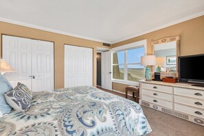 Un dormitorio con cama, cómoda, televisor y ventana con vistas.