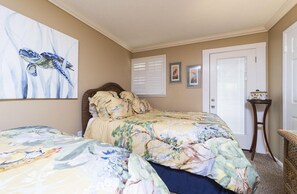 Une chambre à coucher avec un lit, un tableau, une porte et une petite table.