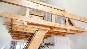 Ein Loft-Zimmer mit freiliegenden Holzbalken, einer geneigten Decke und einer integrierten Küchenzeile.