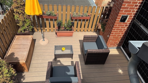 A deck with a wooden floor, a yellow umbrella, and two wicker sofas with cushions. - Loft mit Privater Dachterrasse (Gera)