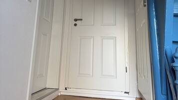 A hallway with a white door, a wooden floor, and a blue wall.