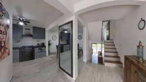 A modern kitchen with dark cabinets, a large island, and a dining area with a bench. There is a staircase leading to an upper level. - Casa Comfy (Cancun)