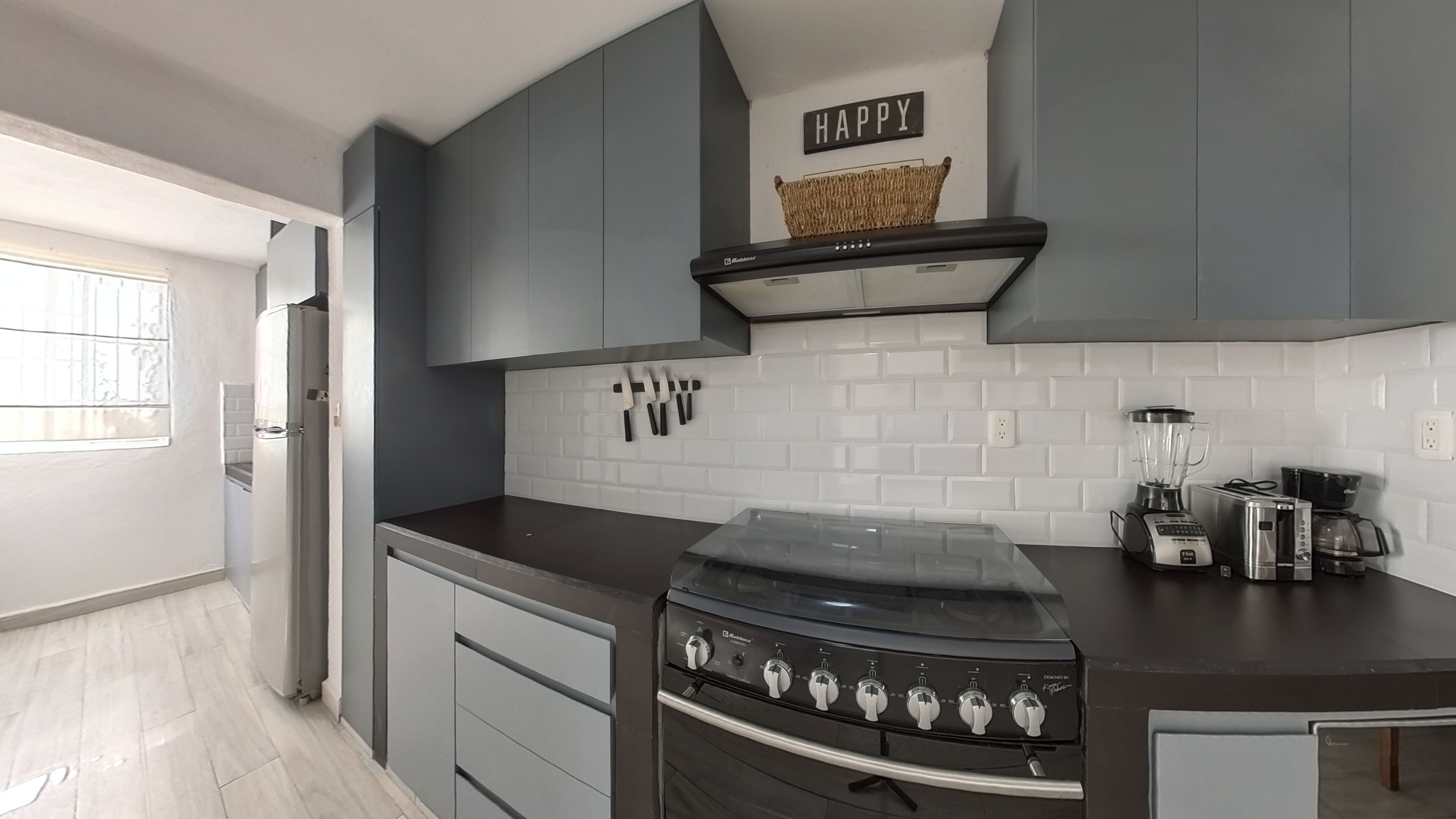 A modern kitchen with grey cabinets, a stainless steel stove, a toaster, and a blender.