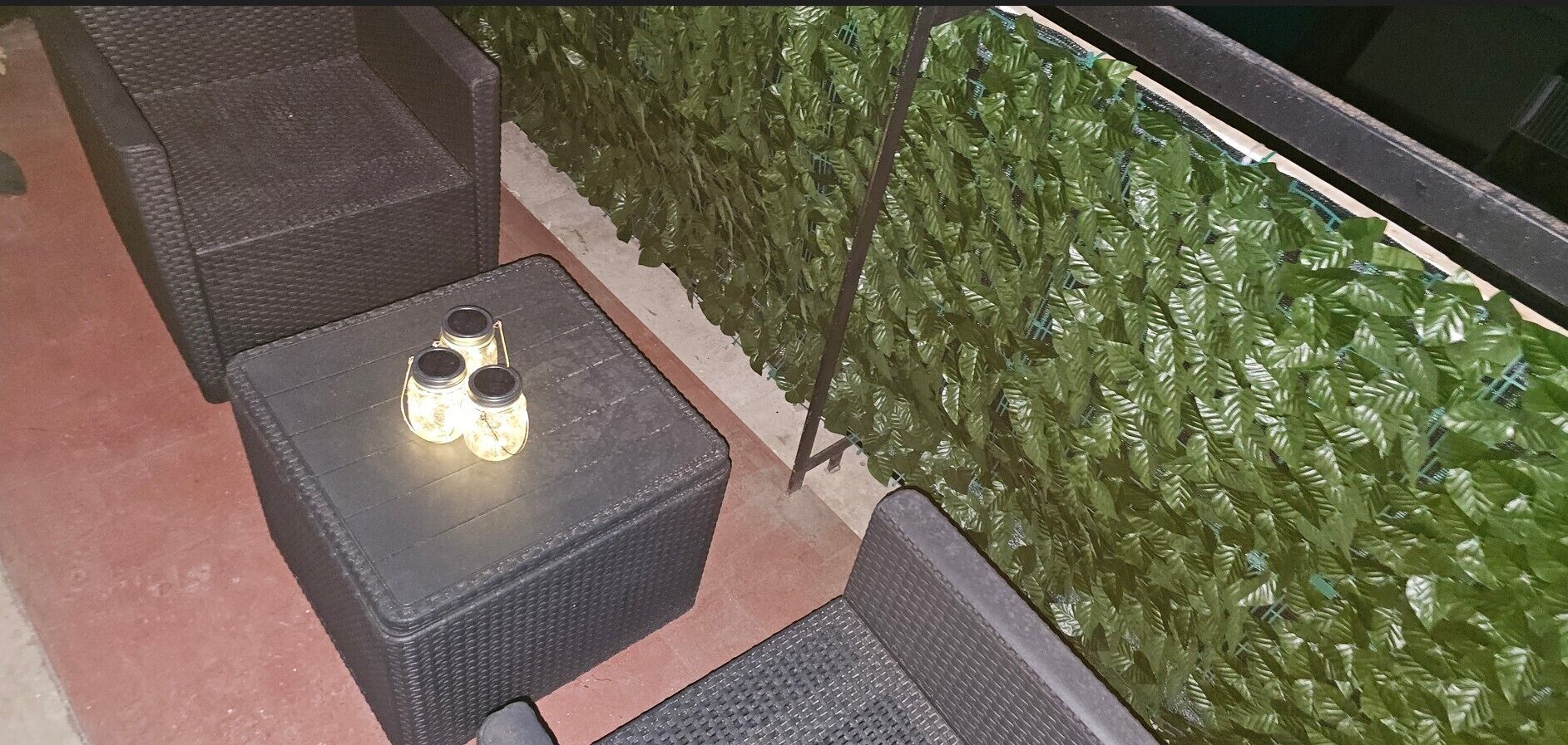 A patio area with a table and chairs, a decorative wall, and a railing.