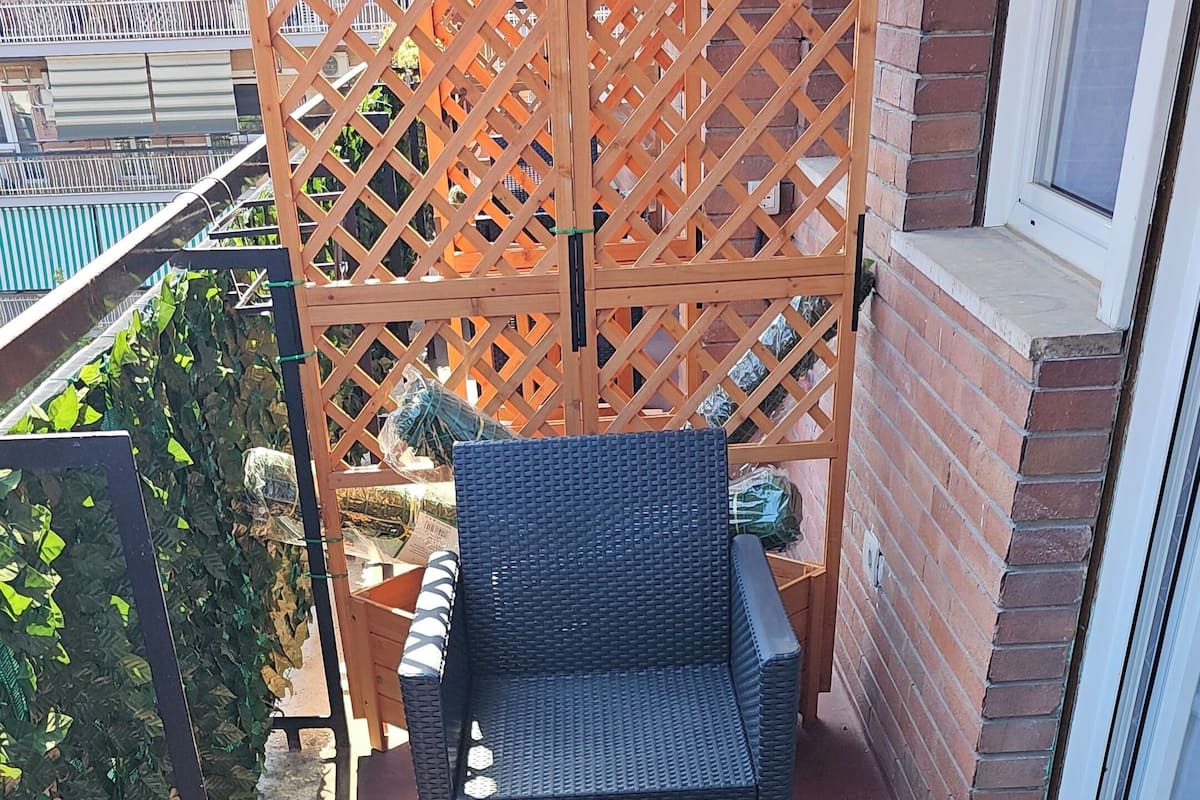 Uma varanda com mobiliário de vime, incluindo duas cadeiras e uma mesa pequena com saleiros.