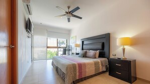 A bedroom with a bed, bedside lamps, a ceiling fan, and a TV mounted on the wall. - Rooftop pool. Luxury apartment in Playa del Carmen (Playa del Carmen)