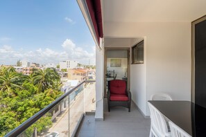 Een balkon met een rode stoel, een witte stoel en een zwarte tafel.