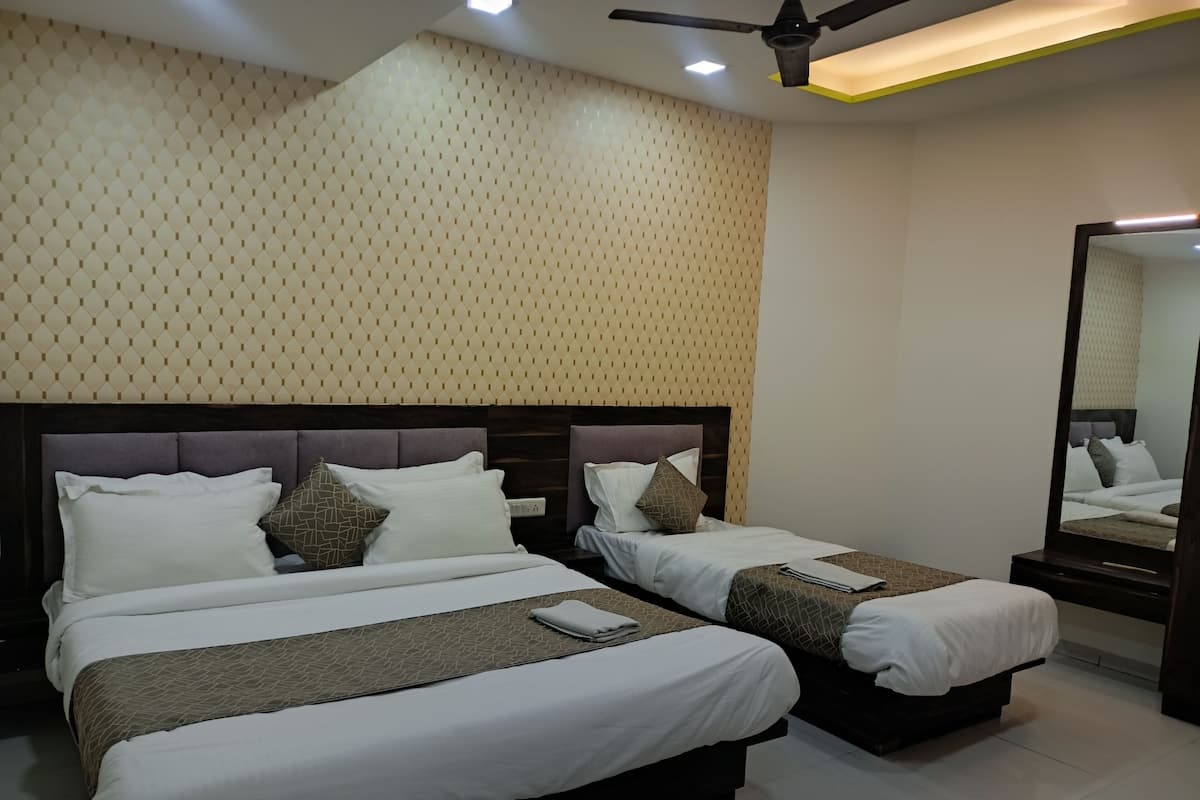 A hotel room with two beds, a ceiling fan, a mirror, and a patterned wall.