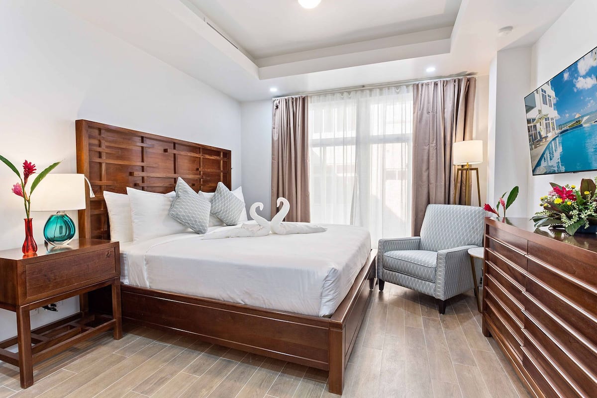 Een hotelkamer met een houten bed, een stoel, een nachtkastje, een lamp en een schilderij aan de muur.