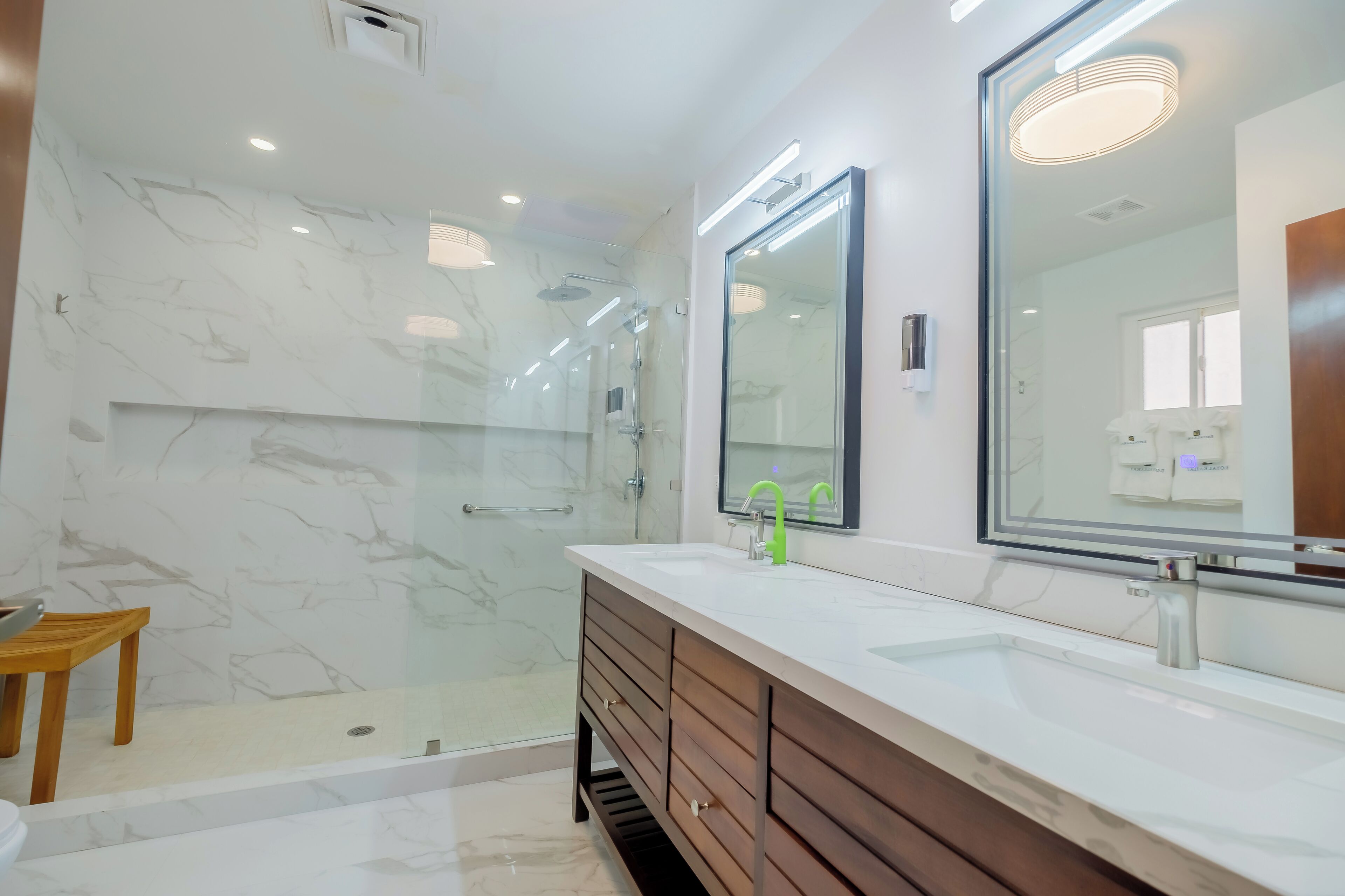 Une salle de bain moderne avec une douche à parois de verre, un meuble-lavabo en bois avec un lavabo blanc et un grand miroir au-dessus du meuble-lavabo.