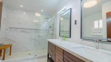 Une salle de bain moderne avec une douche à parois de verre, un meuble-lavabo en bois avec un lavabo blanc et un grand miroir au-dessus du meuble-lavabo.