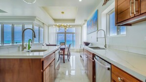 Een moderne keuken met een groot eiland, een eethoek en uitzicht op de oceaan.