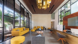 A modern lobby with large windows, a reception desk, and seating areas. - Your cofortable Oasis in Playa del Carmen (Playa del Carmen)
