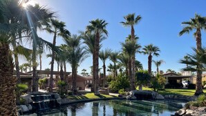 Ein Resort mit Swimmingpool, Palmen und einem Wasserfall.