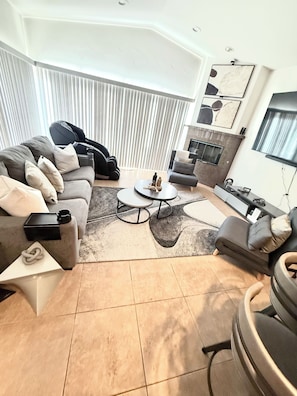 A modern living room with a sofa, armchair, coffee table, and a TV.