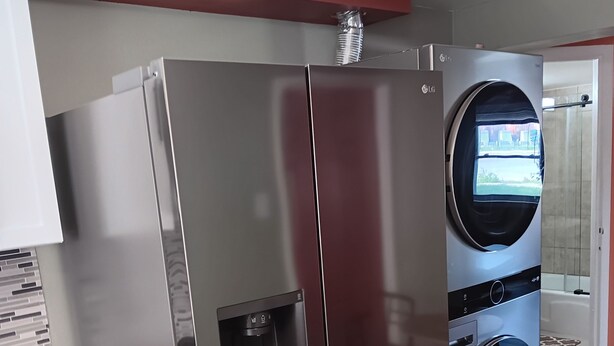 A modern kitchen with a stainless steel refrigerator, a built-in oven, and a washing machine.