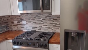 A kitchen with white cabinets, a stainless steel microwave, a gas stove, and a built-in oven.