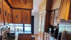 Una cocina con armarios de madera, un refrigerador de acero inoxidable y un horno empotrado.