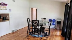 Un comedor con piso de madera, una mesa redonda con sillas y una lámpara de techo.