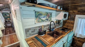 A compact kitchen with wooden countertops, a sink, and a microwave.