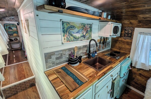 Cocina pequeña con mostradores de madera, un lavamanos y un microondas.