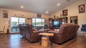 Un salón espacioso con sofás de cuero, una mesa de centro de madera y un televisor.