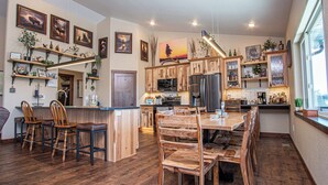 A modern kitchen with wooden cabinetry, a central island with bar stools, and various kitchen appliances.