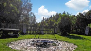 A circular stone structure with a central fire pit, surrounded by a grassy area and a wooden fence. - Amazing apartment in Huta Gorna with WiFi (Huta Gorna)