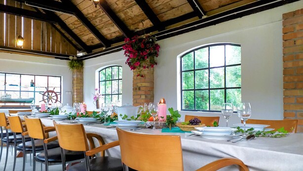 A dining area with a high wooden ceiling, large arched windows, and a ship's wheel decoration. - Amazing apartment in Huta Gorna with WiFi (Huta Gorna)