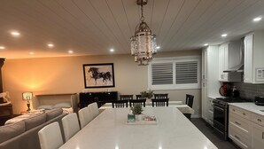 A modern kitchen with a central island, white cabinetry, and a dining area with a table and chairs. - Enjoy creating beautiful memories at Sierra Stables Country Hideaway in 2026 (Langley Township)