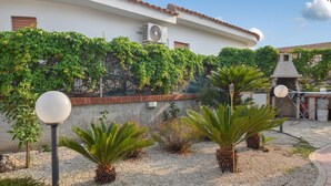 Un patio con un edificio blanco, una estructura de piedra y varias palmeras.