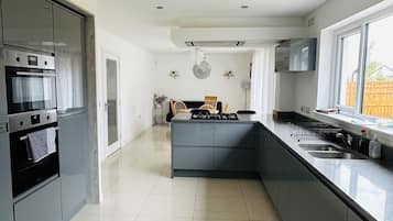 A modern kitchen with grey cabinets, a built-in oven, a central island, and a large window.