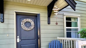 A front door with a wreath, a bench with a pillow, and a 'hello' mat. - Moon shell Cottage-a relaxing cozy retreat for all seasons. (Parksville)