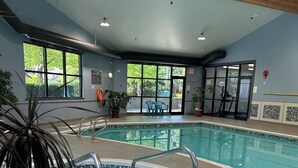 An indoor swimming pool with clear glass walls, a tiled floor, and a wooden ceiling. - Moon shell Cottage-a relaxing cozy retreat for all seasons. (Parksville)