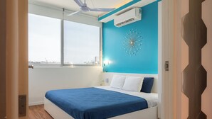 A modern bedroom with a large bed, a ceiling fan, and a view of the city through a large window. - Paradise found. Unique apartment in Playa del Carmen for you (Playa del Carmen)