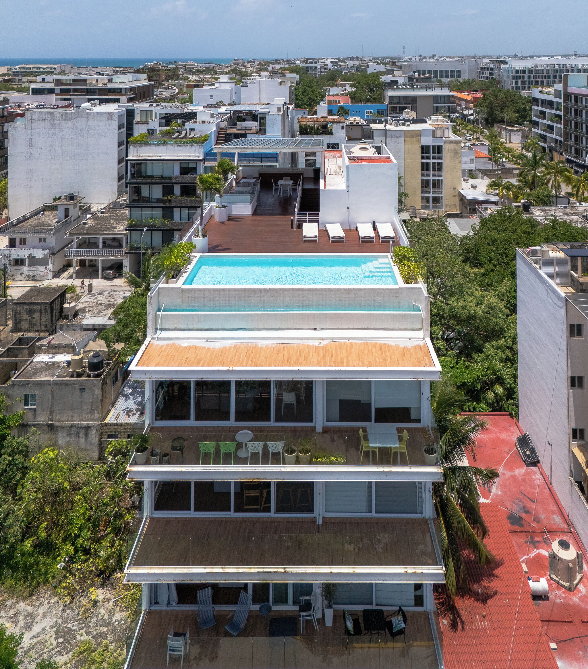 Un immeuble à plusieurs étages doté d’une piscine sur le toit, de nombreux balcons et offrant une vue sur le paysage urbain.