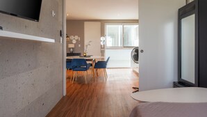 A modern hotel room with a flat-screen TV, a bed, and a dining area with blue chairs and a table. - Paradise found. Unique apartment in Playa del Carmen for you (Playa del Carmen)