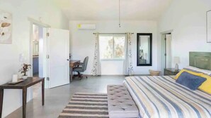 Un dormitorio con una cama, un escritorio, una silla, un ventilador de techo y una ventana con cortinas.
